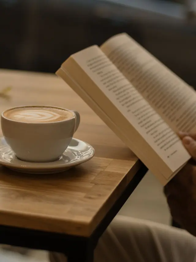 Um cappuccino ao lado de um livro aberto