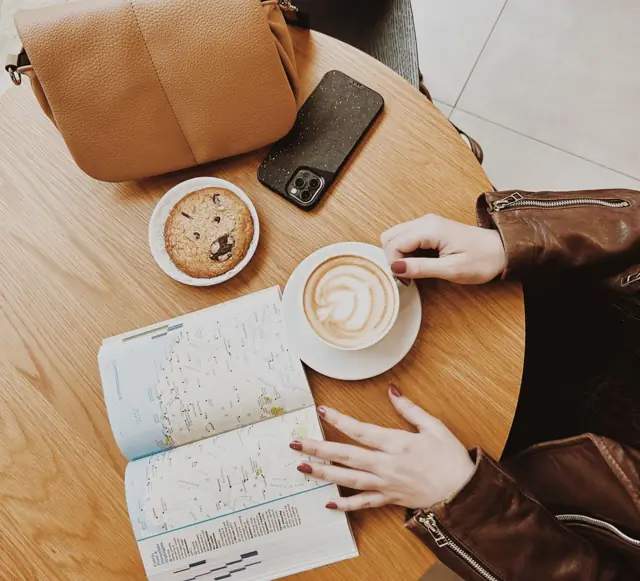 Um cappuccino e um cookie numa mesa ao lado de um mapa de viagem